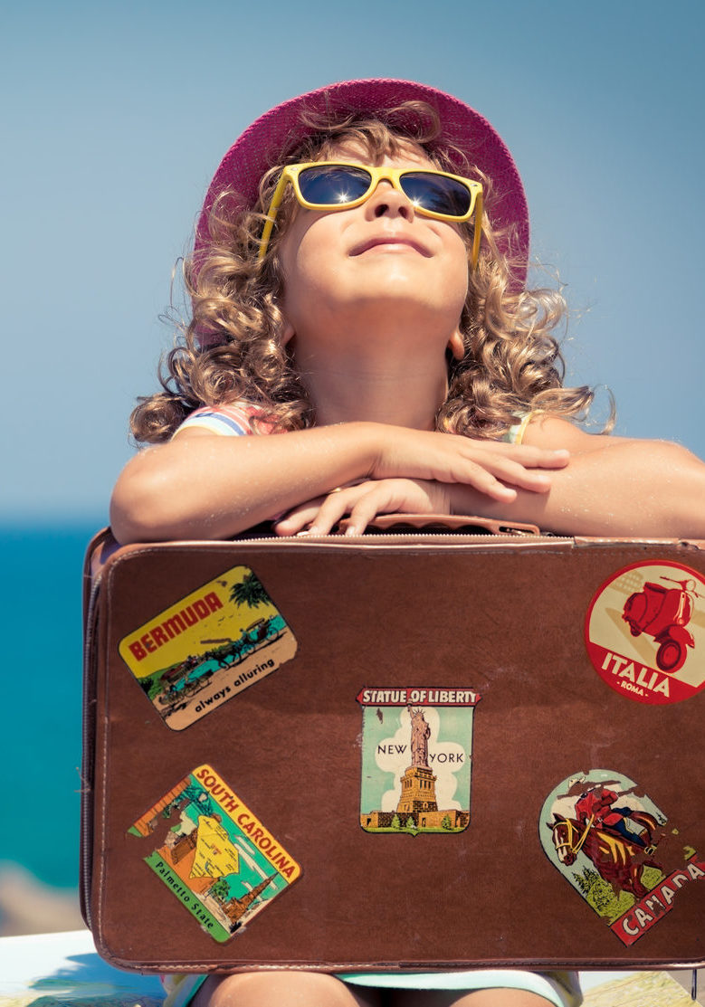 Child with vintage suitcase on summer vacation. Travel and adventure concept