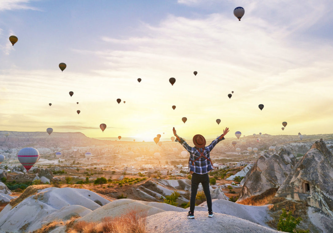 Back of successful traveler guy with open arms in scenic valley in Anatolia, Kapadokya. Beautiful destination in Nevsehir, Goreme